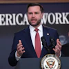 Man in navy suit speaking at podium with Presidential Seal, addressing audience at American Workers event