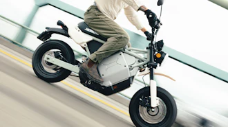 Person riding white and black electric scooter on road with yellow lane marking