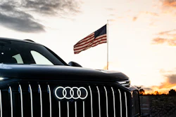 Black Audi vehicle with American flag at sunset