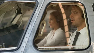 Two people seated in vintage aircraft cabin with sunlight streaming through windows