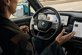 Driver with hands on steering wheel inside modern autonomous vehicle with digital dashboard display