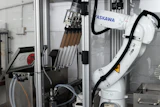 ASKAWA industrial robotic arm with tool changer mounted in manufacturing enclosure