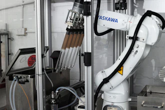 ASKAWA industrial robotic arm with tool changer mounted in manufacturing enclosure