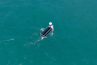 Aerial view of a pontoon boat on clear turquoise water with white canopy