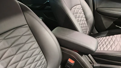 Luxury car interior with quilted leather seats in light gray and black tones, center console visible