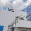Smurfit Westrock industrial manufacturing facility with blue logo on corrugated metal building and storage tanks