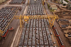 Aerial view of busy shipping port with hundreds of stacked containers, yellow gantry cranes, and cargo handling equipment