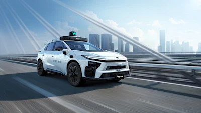 White autonomous taxi vehicle with blue accents driving on elevated highway with city skyline in background