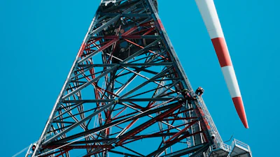 Tall telecommunications tower with red and white striped antenna against clear blue sky